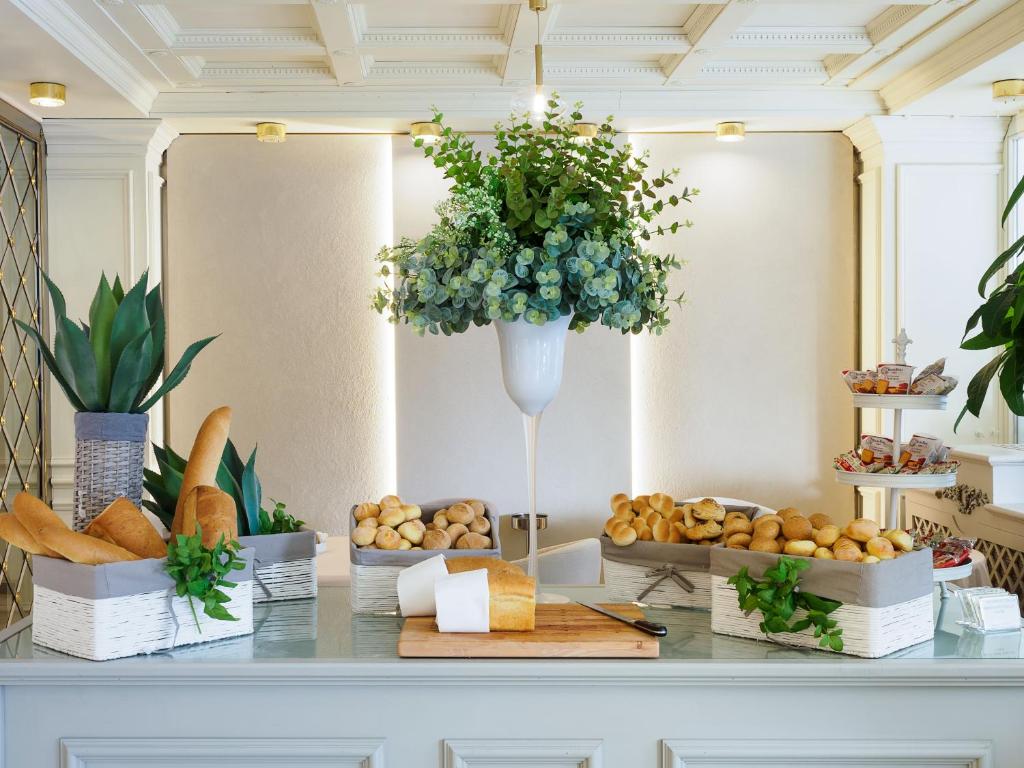 Svaigu maizes izstrādājumu bufete ar dekoratīvām zālēm un stilīgu interjeru, kurā redzamas dažādas maizes un bulciņas, veidojot viesmīlīgu atmosfēru.