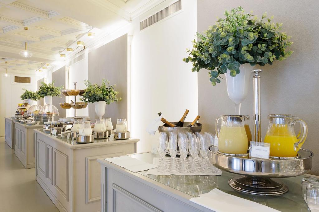 Eleganta bufete ar dažādiem dzērieniem un uzkodām, dekorēta ar zaļumiem un gaismas elementiem. Ideāla vieta svinībām un pasākumiem.