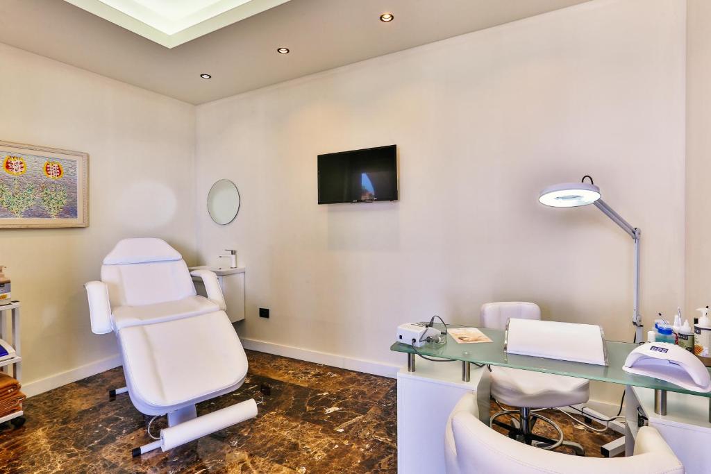 Skaista un moderna estētiskās procedūras telpa ar baltām sienām, ērtu krēslu un darba galdu, kurā ir nepieciešamie rīki un aprīkojums. Telpā ir arī televizors un liels spogulis.
