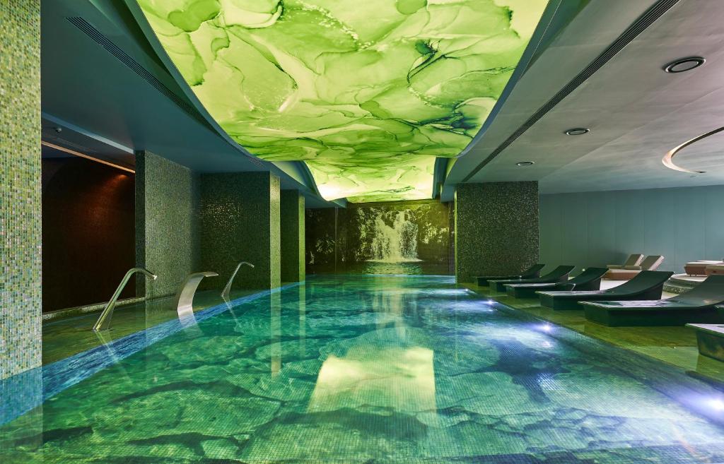 Mūsdienīgs spa ar gleznainu iekšējo baseinu, kas atspoguļo zaļas krāsas un relaksējošu atmosfēru. Ideāla vieta atpūtai un labsajūtai.