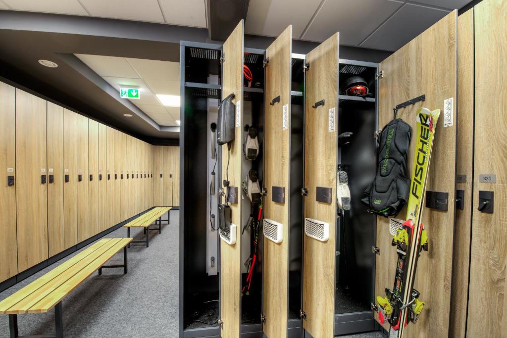 Skatuves telpa ar slēgtām un atvērtām skapīšiem, kur redzami slēpošanas aprīkojumi, kā arī koka solu rinda. Skapīši ir moderni un funkcionāli.