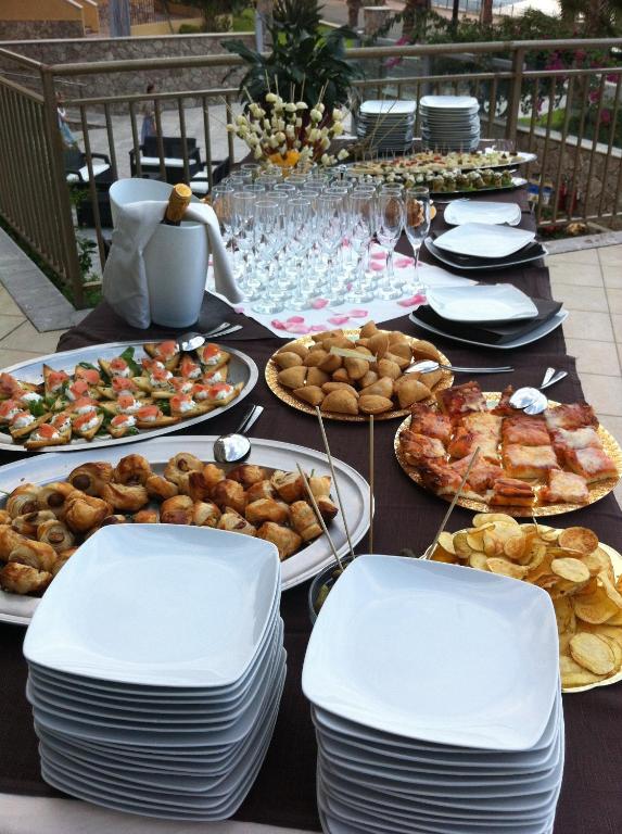 Svētku mielasts ar dažādiem uzkodu šķīvjiem, tostarp laša un maizes izstrādājumiem, kā arī dzērienu glāzēm un dekoratīviem elementiem. Ideāli piemērots svinībām un pasākumiem.