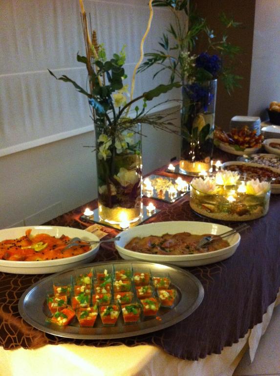 Elegantā galda klāšana ar dažādām delikatesēm un dekoratīvām puķēm, radot svinīgu atmosfēru. Saldēti un sālīti ēdieni, kā arī izsmalcināti uzkodu trauki ir izkārtoti uz galda.