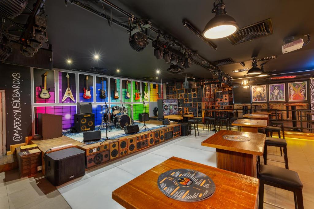Citymax al Barsha mūzikas bārs ar skatuvi un ģitārām uz sienas.