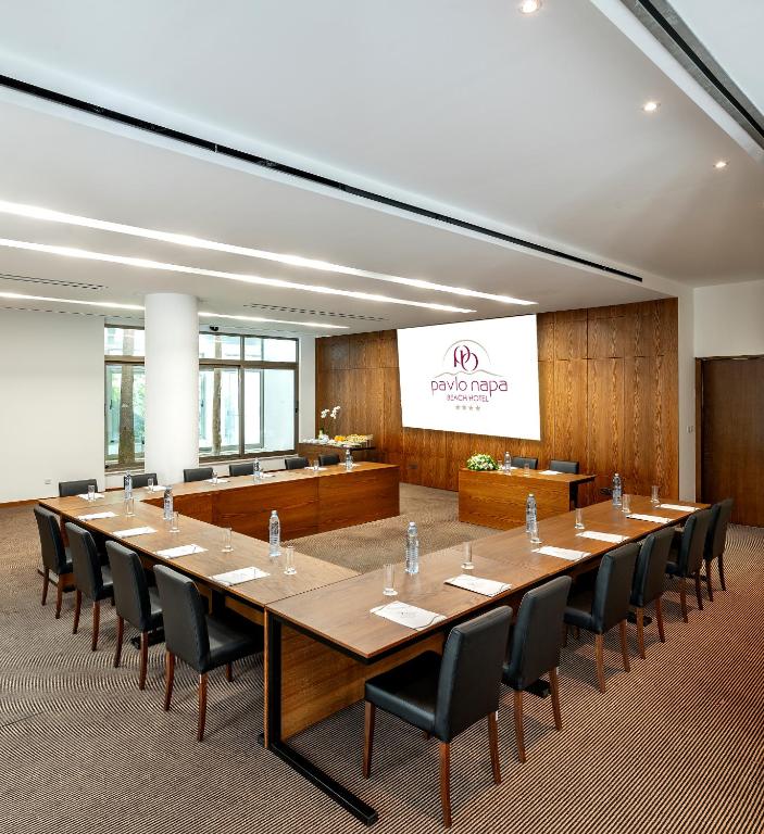 Konferenču telpa ar modernu interjeru un koka akcentiem, aprīkota ar galdiem un krēsliem, kā arī prezentācijas ekrānu. Telpā ir dabisks apgaismojums un zaļumi.