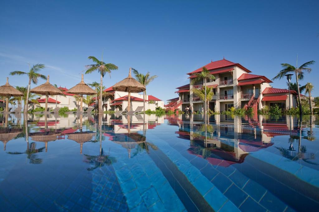 Tamassa Bel Ombre viesnīca piekrastē ar baseinu un palmu ainavu.