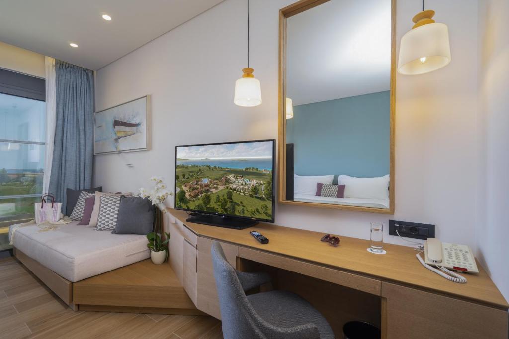 Mūsdienīga viesnīcas numura interjers ar plašu logu, televizoru un ērtu atpūtas stūri. Gaiši toņos iekārtots, radot mājīgu atmosfēru.