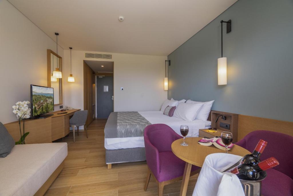 Mūsdienīgs viesnīcas numurs ar ērtu gultu, nelielu virtuvīti un viesistabu, kurā ir televizors un galdiņš ar vīna glāzēm. Telpa ir gaiša un silta, ar neitrālām krāsām un modernu dizainu.