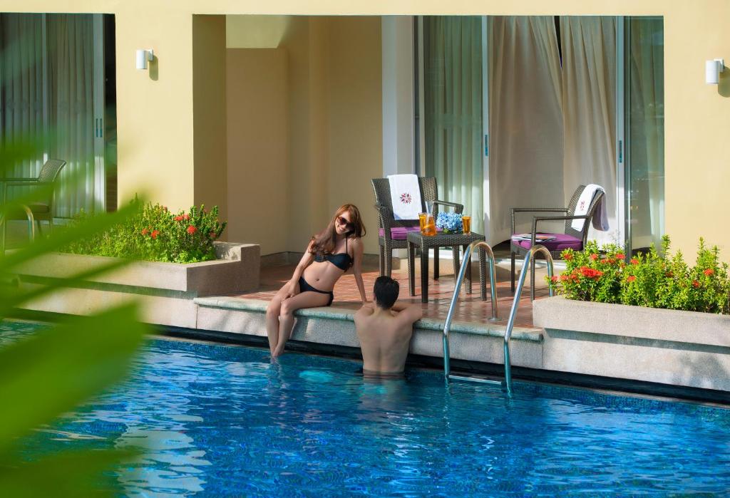 Pāris atpūšas pie Angsana Laguna Phuket baseina, baudot sauli.