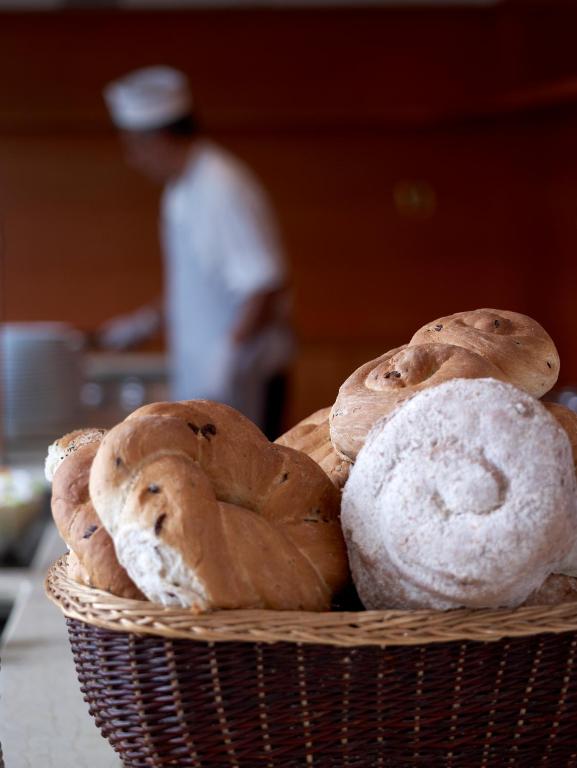 Maizes grozs ar dažādām maizes šķirnēm, fona attēlā redzams pavārs.