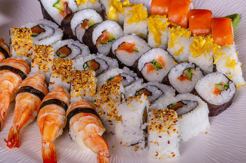 Svaigu sushi un garneles uz šķīvja, piedāvājot daudzveidīgas garšas un krāsas. Ideāls ēdiens sushi mīļotājiem.