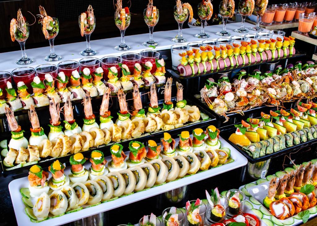 Svaigu jūras velšu un sushi bufete ar dažādām garšām un krāsām, kas izkārtota uz melnas virsmas. Izcilas garneles, dārzeņi un rīsi veido pievilcīgu ēdienu kombināciju.