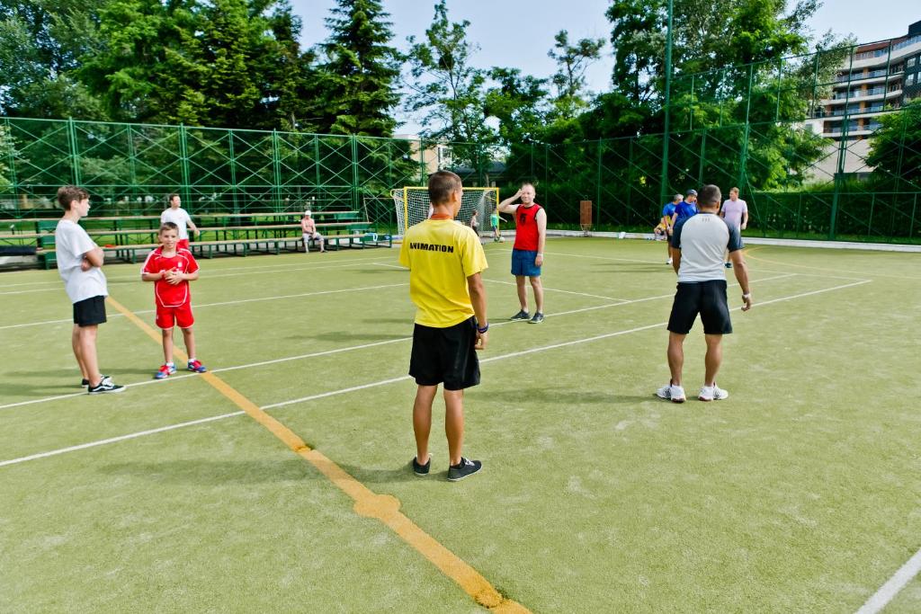 Bērni un pieaugušie piedalās sporta aktivitātēs uz futbola laukuma, kurā notiek apmācības un spēles. Darbojas treneri un dalībnieki, kas nodarbojas ar fiziskām aktivitātēm.