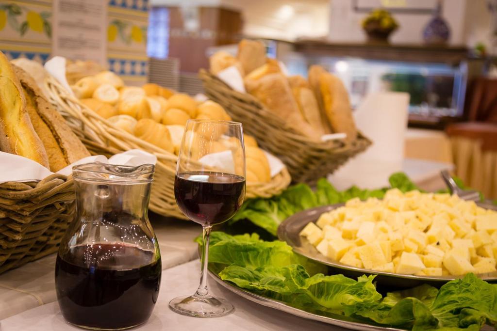 Svaigi ceptas maize, vīna krūze un siera šķēlītes uz galda ar zaļajiem salātiem. Ideāla atmosfēra viesību vai svētku mielastam.