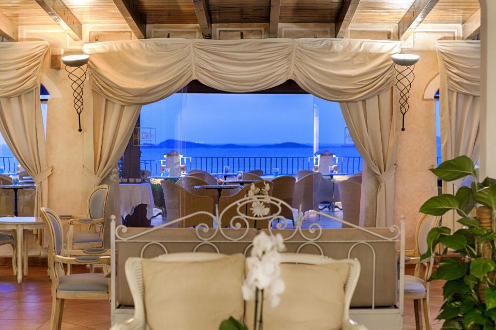 Elegants restorāns ar panorāmas skatu uz jūru, izsmalcinātiem galdiem un krēsliem, kā arī patīkamu interjeru. Gaisma un dekors rada relaksējošu atmosfēru.