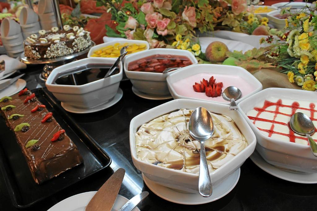 Saldumu galda ar dažādām desertu bļodiņām, šokolādes kūku un augļiem. Ideāla izvēle svinībām un saldummīļiem.