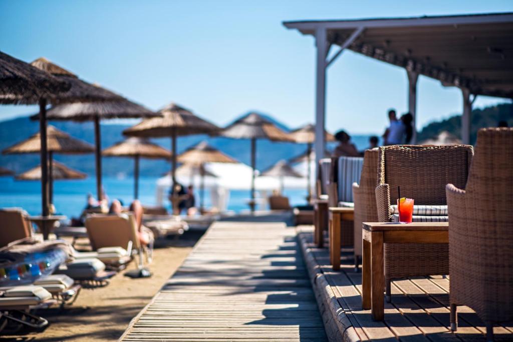 Pludmales atmosfēra ar saulainu skatu uz jūru, kur koka terasē redzami ērtie krēsli un salda dzira. Ideāla vieta relaksācijai un atpūtai.