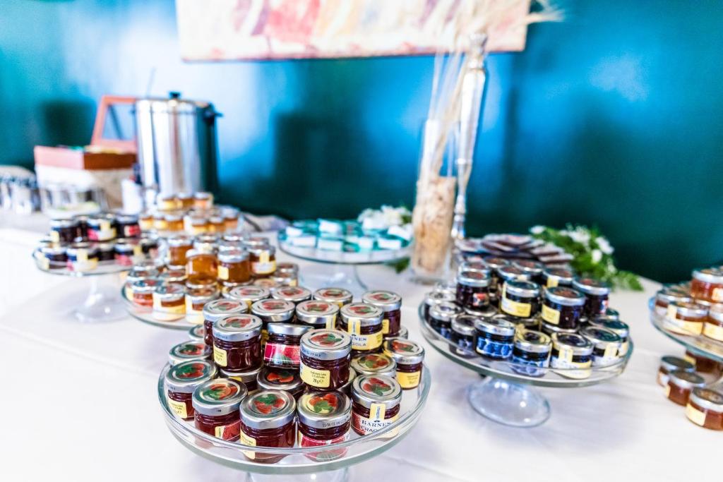 Dažādu ievārījumu un želeju izkārtojums uz galda, ar glītām burciņām un elegantu apkalpošanu. Ideāla izvēle kulinārijas pasākumiem vai svinībām.