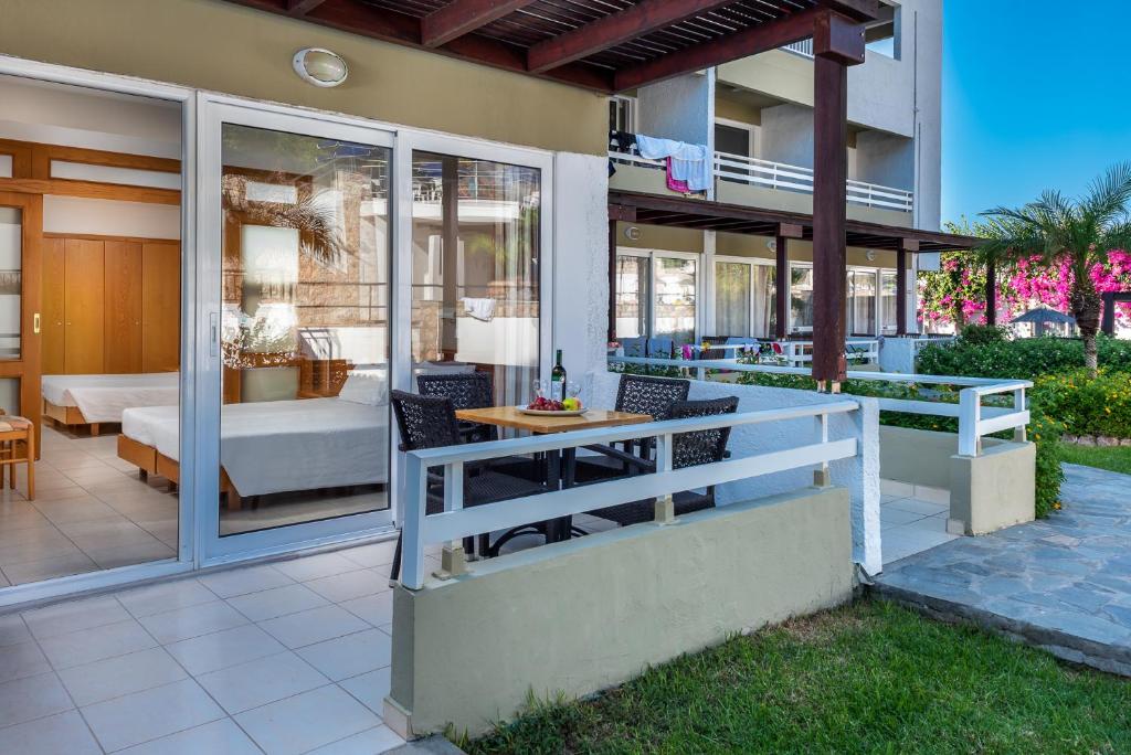 Mūsdienīga viesnīcas terase ar galdu un krēsliem, kas paveras uz dārzu un viesnīcas numuru. Ievērojama gaisīga atmosfēra un ziedu apstādījumi.