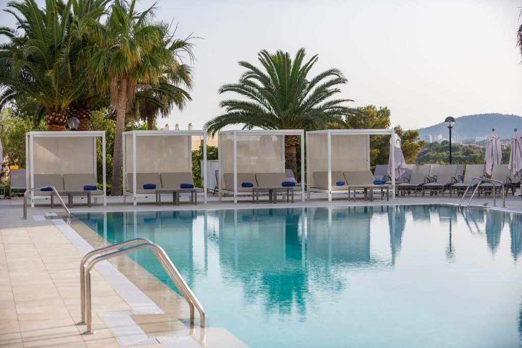 Skaista baseina zona ar palmām un atpūtas gultām, ideāla relaksācijai un atpūtai saulainā laikā.