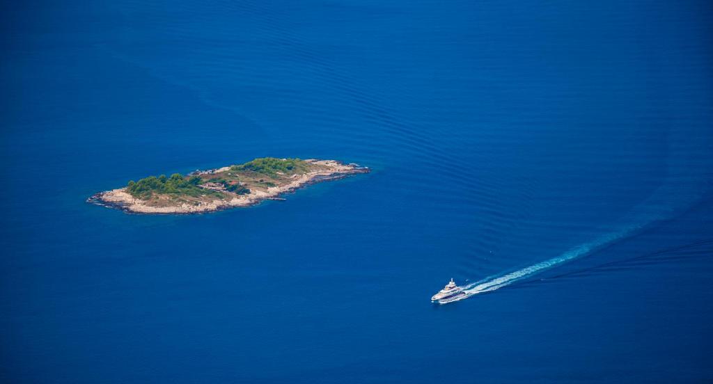 Mazs, apzaļumots izsāls ar skaidru ūdeni apkārt un jahta, kas to appeld.