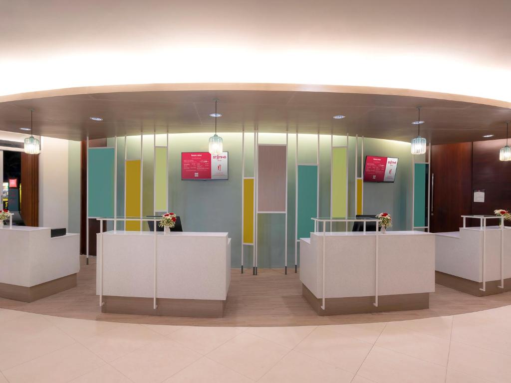 Mūsdienīgs reģistratūras dizains ar spilgtām krāsām un elegantām gaismas ķermeņiem, nodrošinot viesmīlīgu atmosfēru. Dekorācijas un izkārtojums rada patīkamu un pievilcīgu vidi.