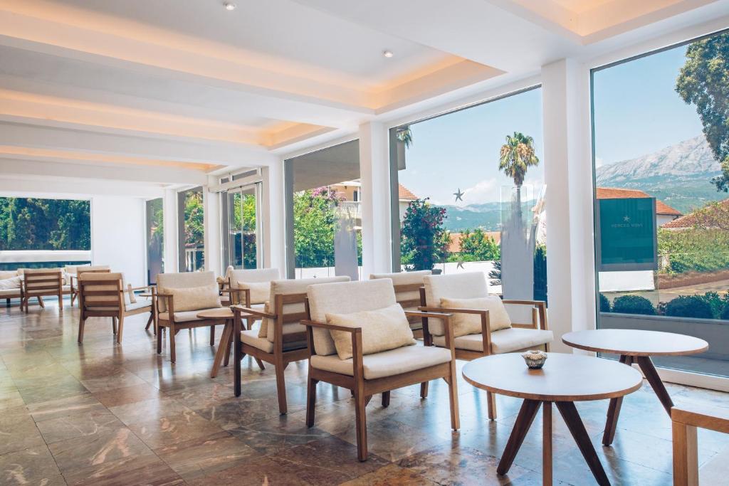 Mūsdienīgs viesnīcas vestibils ar ērtām koka mēbelēm un plašiem logiem, kas piedāvā skatu uz dārzu un kalniem. Gaismas elementi un dabiskā apgaismojuma klātbūtne rada relaksējošu atmosfēru.