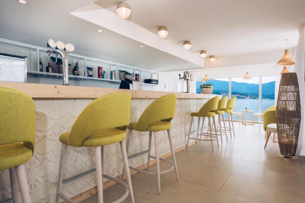 Mūsdienīgs bārs ar gaišām krēsliem un skatu uz jūru, radot relaksējošu atmosfēru. Interjers ir elegants, ar gaišām krāsām un dabīgiem elementiem.