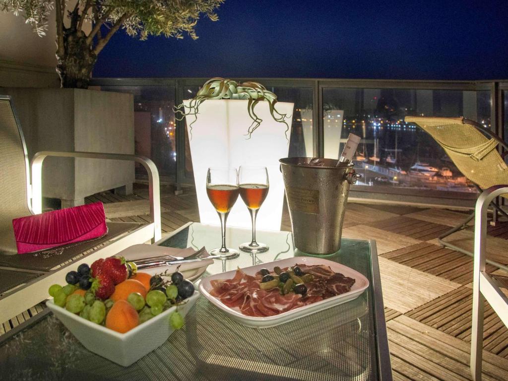 Romantiska vakara uzkodas ar augļiem un gaļas šķēlītēm, divas glāzes dzēriena un ledus spainis uz terases naktī.