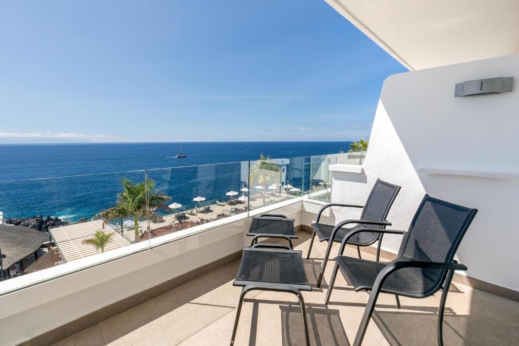 Balcony ar skatu uz jūru, kur izvietoti vairāki krēsli un palmas. Ideāli piemērots relaksācijai un atpūtai.