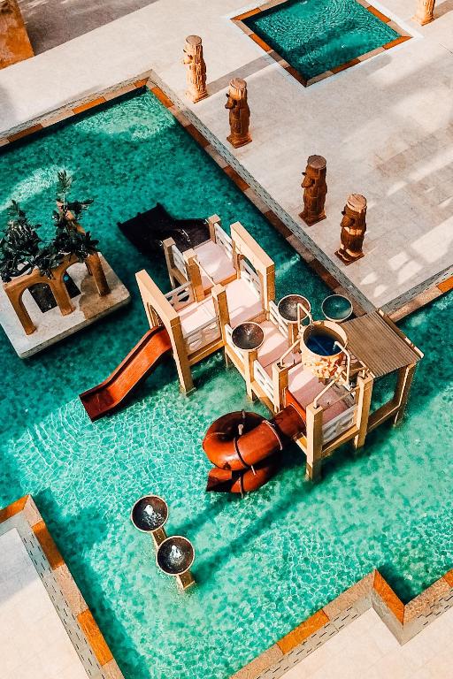 Peldbaseins ar slidkalniņu un atpūtas zonu, ieskauts ar akmens skulptūrām un zaļām augiem. Ideāla vieta relaksācijai un izklaidei.