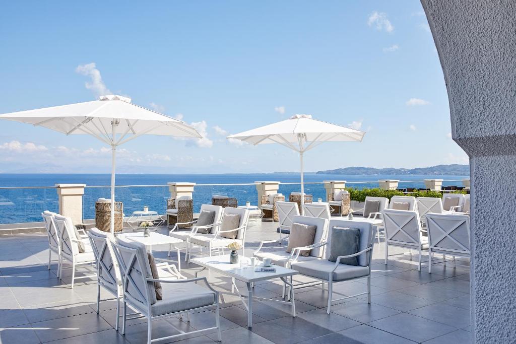 Sauļošanās zona ar baltiem krēsliem un saulessargiem, kas izskatās uz mierīgu jūru un debesīm. Ideāla vieta relaksācijai un atpūtai.