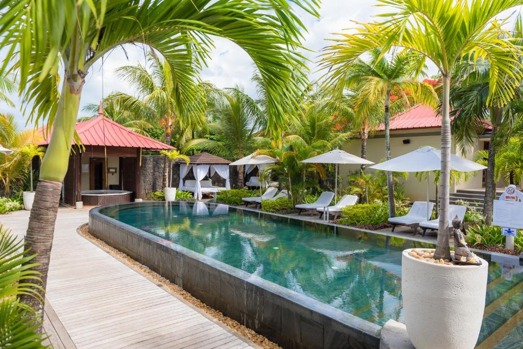 Viesnīcas Tamassa Bel Ombre peldbaseins ar palmām un saulessargiem.