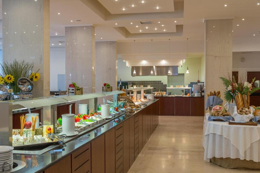 Eleganta bufete ar dažādiem ēdieniem un dzērieniem, iekārtota modernā restorānā. Uzsvars uz svaigiem augļiem, maizēm un dekoratīvām kompozīcijām.