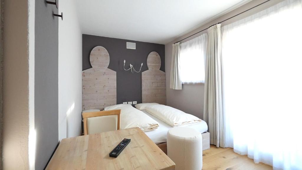 Mūsdienīgs guļamistabas interjers ar divguļamo gultu, koka mēbelēm un gaišām aizkariem, kas ļauj dabiskai gaismai ieplūst telpā.