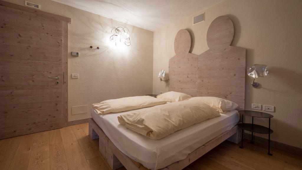 Mūsdienīga guļamistaba ar divguļamo gultu, koka sienu paneli un unikālu dekoratīvo apgaismojumu. Interjers ir vienkāršs, bet elegants, radot relaksējošu atmosfēru.