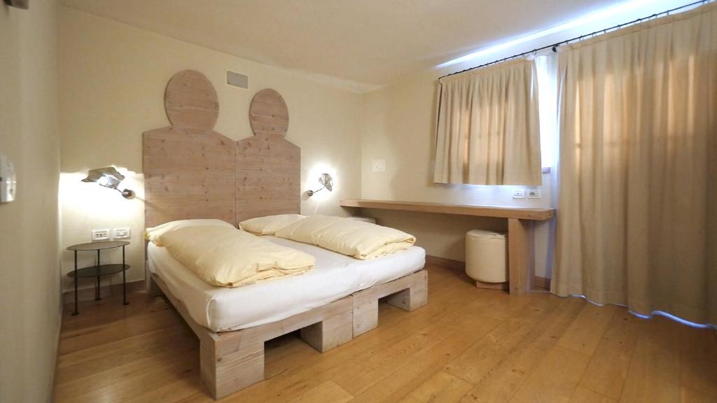 Mūsdienīga guļamistaba ar koka mēbelēm, divguļamo gultu un dabiskiem apgaismojuma elementiem. Telpā ir arī liels logs ar aizkariem un koka grīda, radot siltu un mājīgu atmosfēru.