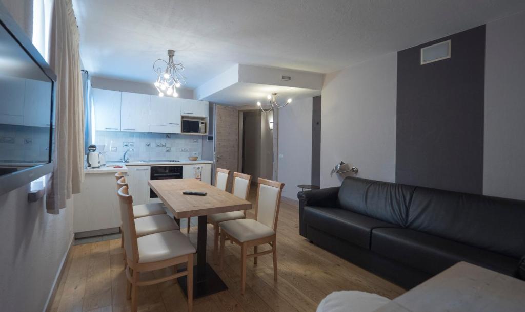 Mūsdienīgs dzīvojamās istabas interjers ar ēdamgaldu un virtuvi. Gaišas krāsas un koka grīdas rada siltu atmosfēru.