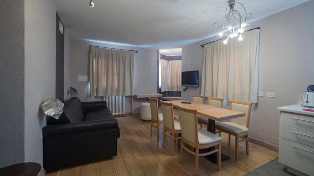 Mūsdienīgs viesistabas un ēdamistabas interjers ar pelēkām sienām, koka grīdu un ērtu dīvānu. Interjeru papildina gaismeklis un televizors, sniedzot mājīgu atmosfēru.