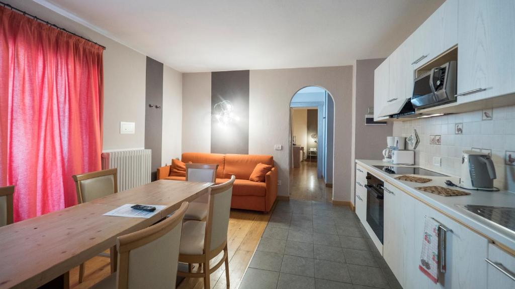 Mūsdienīgs virtuve un dzīvojamā istaba ar koka galdu, oranžu dīvānu un sarkaniem aizkariem, radot viesmīlīgu atmosfēru. Izskatīgas virtuves iekārtas un plašs interjers.