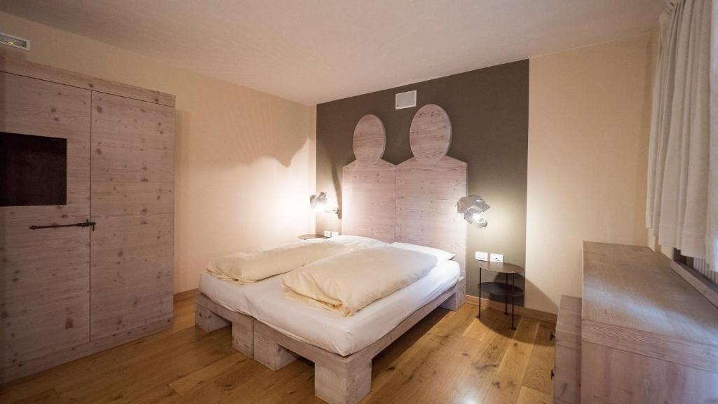 Mūsdienīga guļamistaba ar koka mēbelēm, divguļamo gultu un stilīgu apgaismojumu. Telpa iekārtota ar neitrālām krāsām un dizaina elementiem.