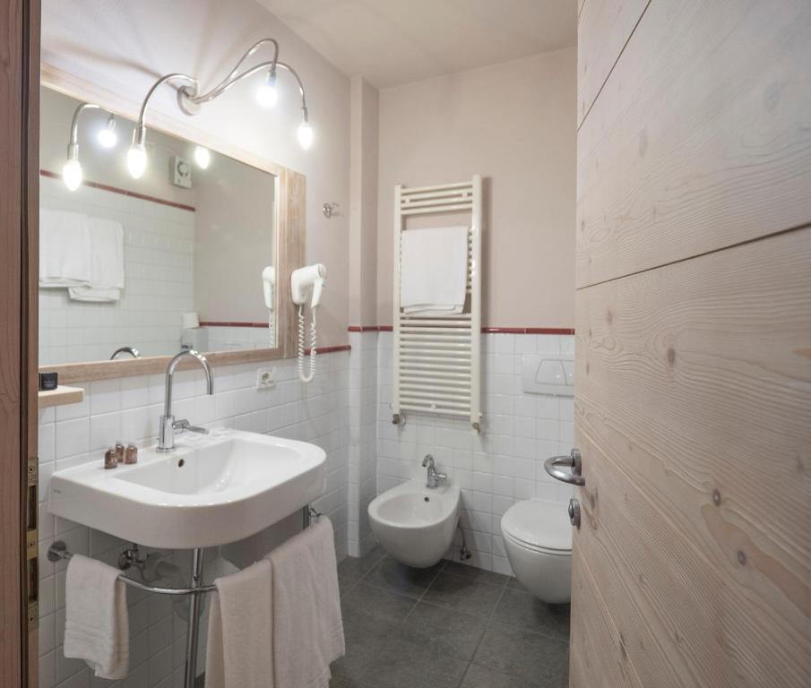 Moderns vannas istabas interjers ar baltiem flīzēm, dušas jaucējkrānu un bidē. Apgaismojums un spogulis piešķir telpai elegantu izskatu.