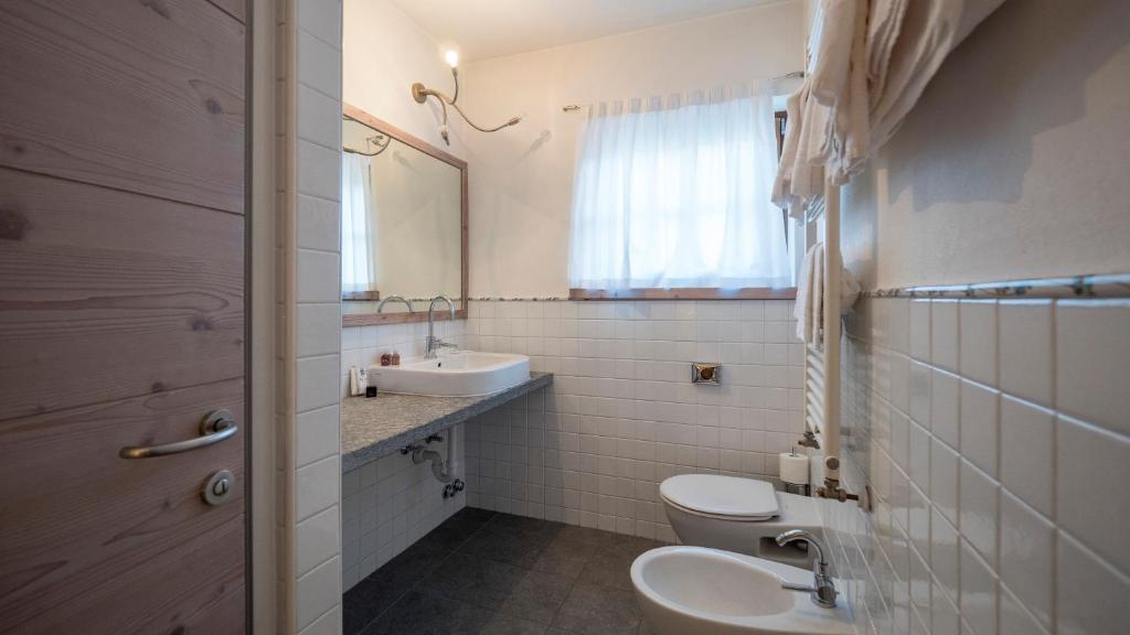 Mūsdienīgs vannas istabas interjers ar gaišu gaismu, akmens izskata izlietni un diviem sanitārajiem izstrādājumiem. Gaisīga atmosfēra ar logu, kas apgaismo telpu.