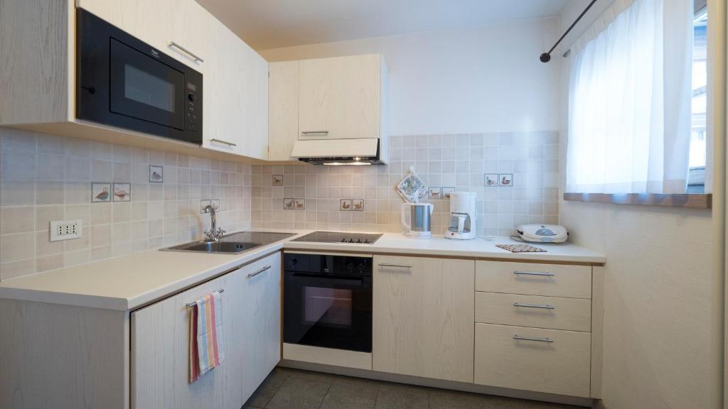 Mūsdienīga virtuve ar gaišiem skapjiem, mikroviļņu krāsni un plīti, kas nodrošina funkcionālu un estētisku vidi. Gaitenī ir arī kafijas automāts un citas mājsaimniecības ierīces.