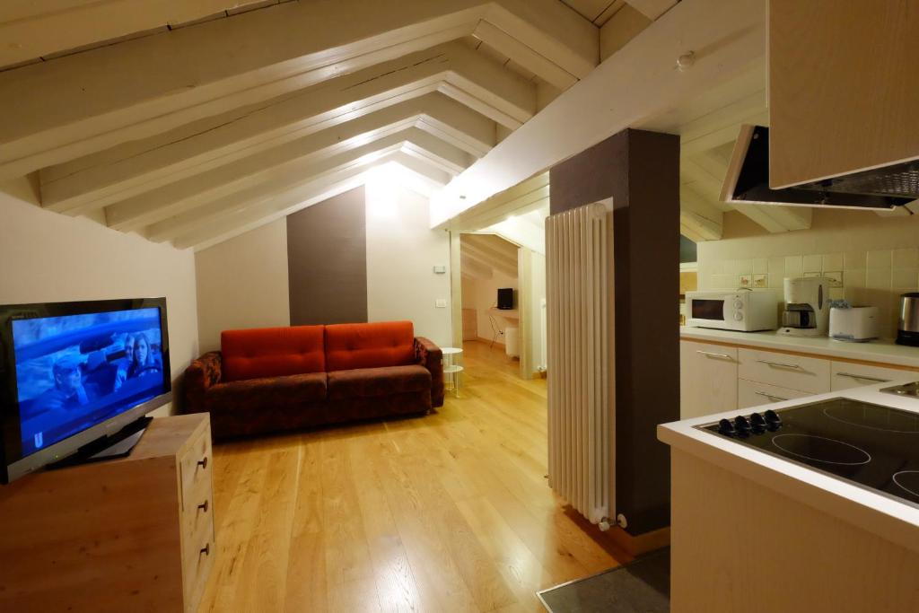 Mūsdienīga bēniņu dzīvokļa interjers ar viesistabu, sarkanu dīvānu un televizoru. Virtuve ar modernām ierīcēm un koka grīdu.