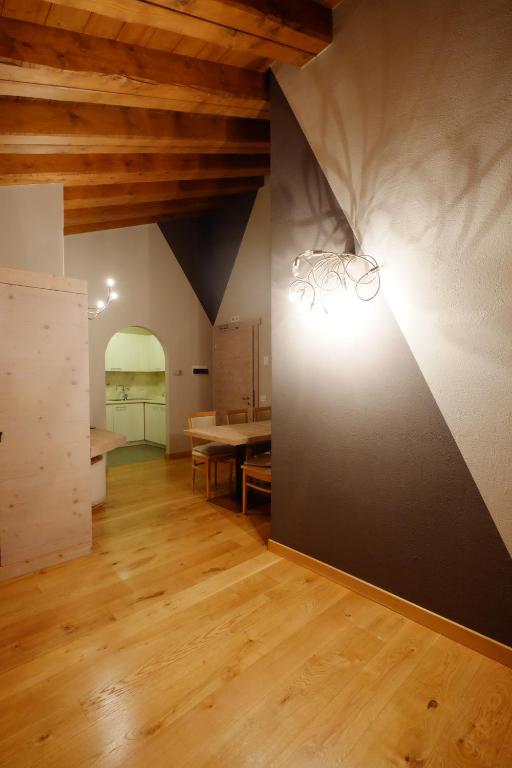 Mūsdienīgs interjers ar koka griestiem un stilīgu apgaismojumu, kas radījis siltu un mājīgu atmosfēru. Redzama ēdamzona un daļa no virtuves, kas atrodas gaišā telpā.