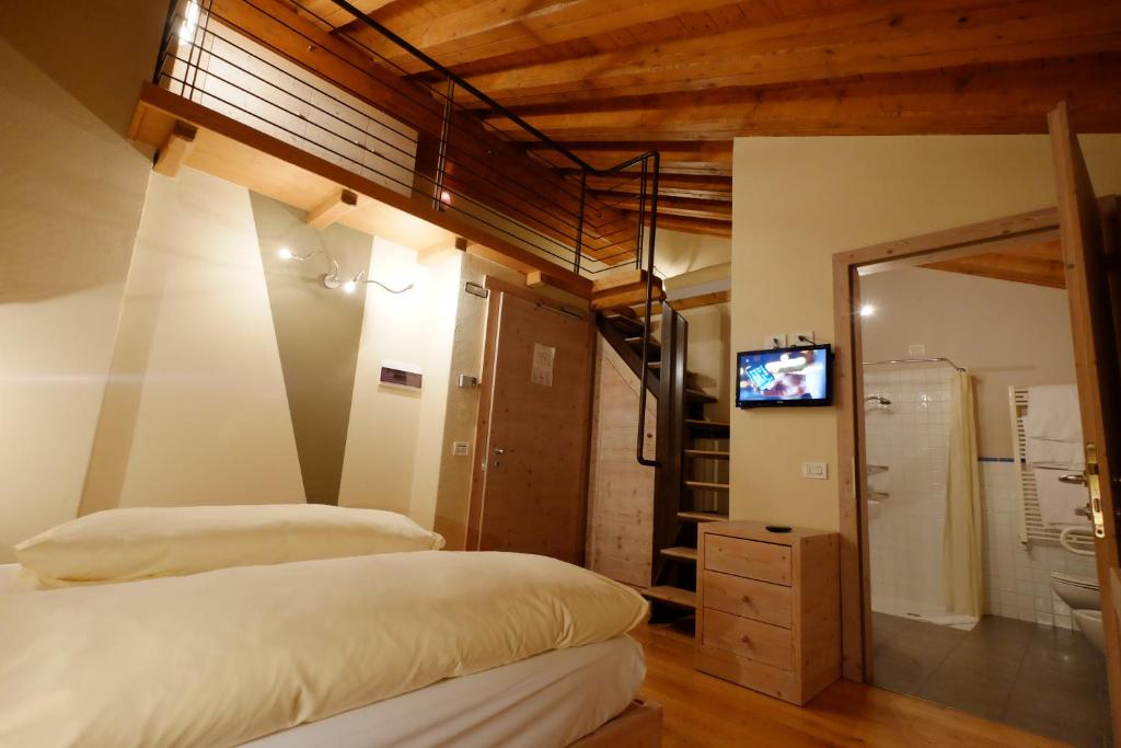 Mūsdienīga guļamistaba ar koka griestiem, ērtiem gultas veļas piederumiem un piekļuvi vannas istabai. Telpā ir televizors un kāpnes uz otro stāvu.