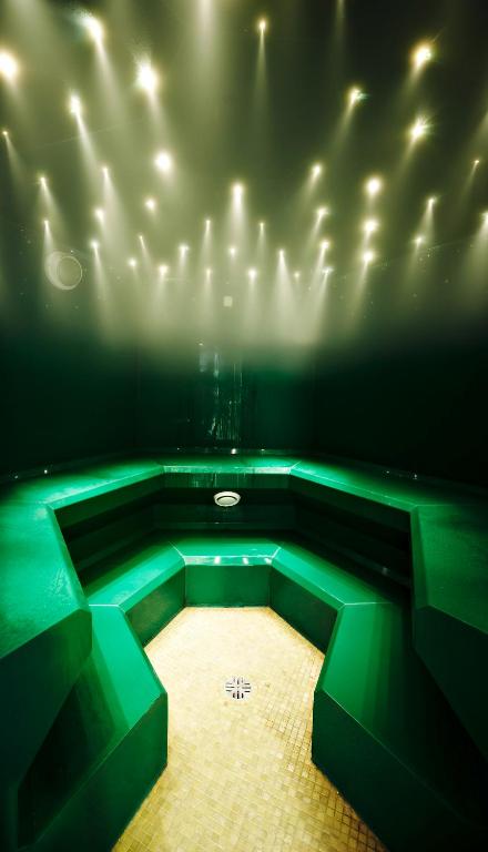 Zaļš tvaika pirts iekšējais skats ar modernu apgaismojumu un daudzām gaismiņām uz griestiem. Pirts ir veidota ar daudzām sēdvietām, kas nodrošina relaksējošu atmosfēru.