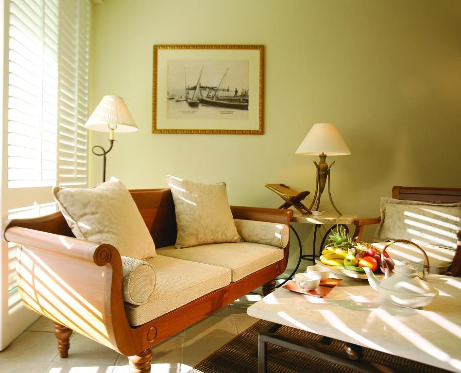 Skaists un mājīgs dzīvojamās istabas stūris ar elegantu dīvānu, apgaismojumu un augļu trauku uz galda. Interjers ir gaišs un izsmalcināts, radot relaksējošu atmosfēru.