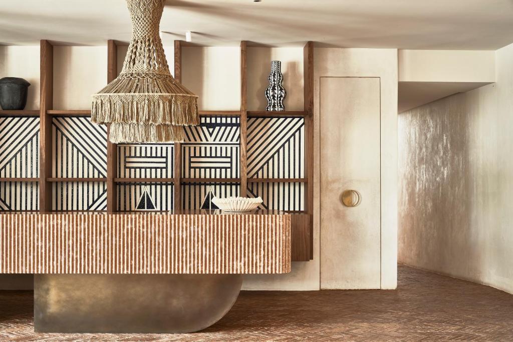 Mūsdienīgs interjers ar elegantu koka letīti, rotātu ar ģeometriskām līnijām un izsmalcinātu lampu. Fons veidots ar melnbaltām dekorācijām, radot siltu un viesmīlīgu atmosfēru.